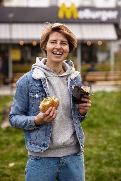 Ragazza che mangia un hamburger con fast food