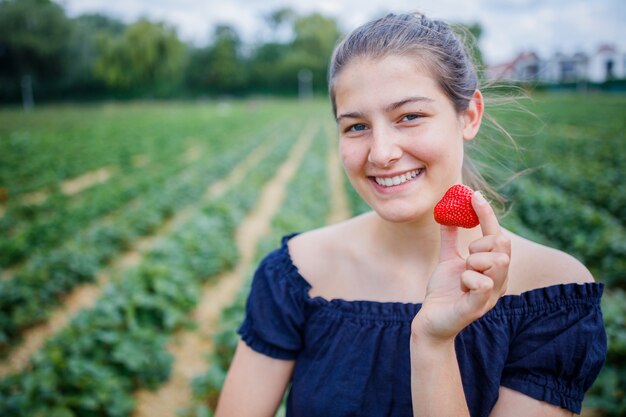 ragazza che mangia una fragola mentre raccogli le fragole in un campo