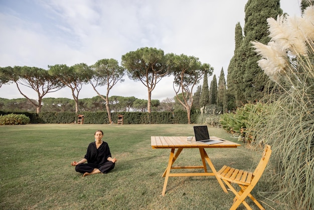 Ragazza che medita e pratica yoga sul prato verde