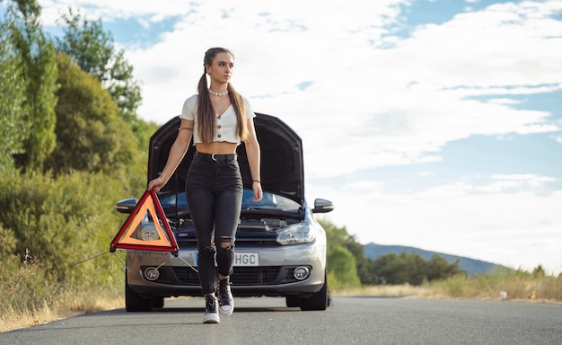 Ragazza che mette un triangolo davanti alla macchina