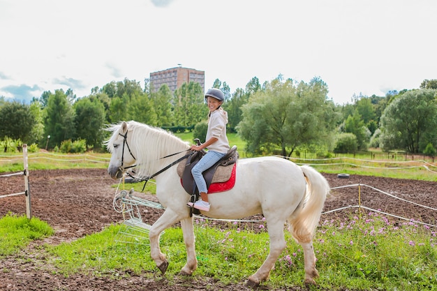 Ragazza che monta un cavallo bianco sulla natura