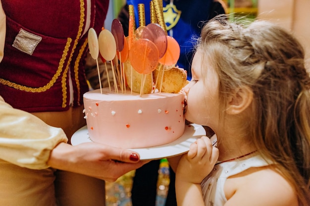 Ragazza che morde la festa dei bambini della torta di compleanno festiva