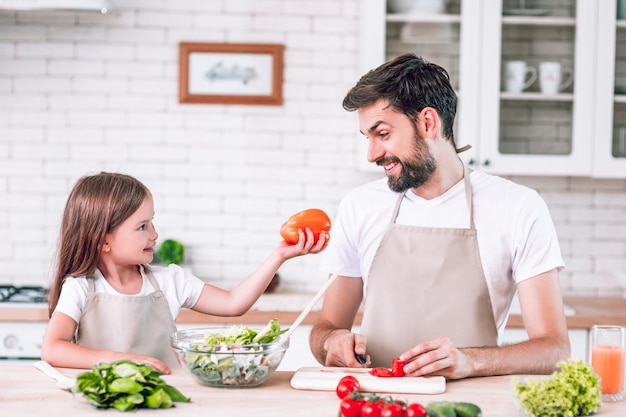 Ragazza che mostra a suo padre il peperone dolce sulla cucina domestica