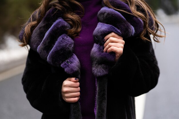 Ragazza che mostra alla fotocamera maglione elegante, viola alla moda cappotto di pelliccia.