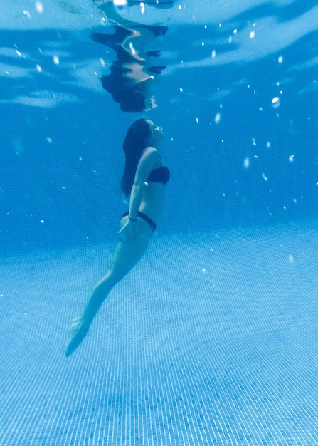 ragazza che nuota sotto la piscina