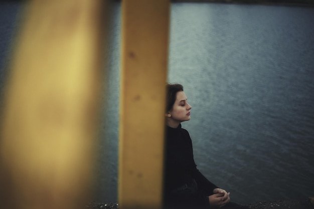 Ragazza che opprime la solitudine vicino al lago d'acqua adolescente da sola in solitudine che cerca di far fronte all'isolamento