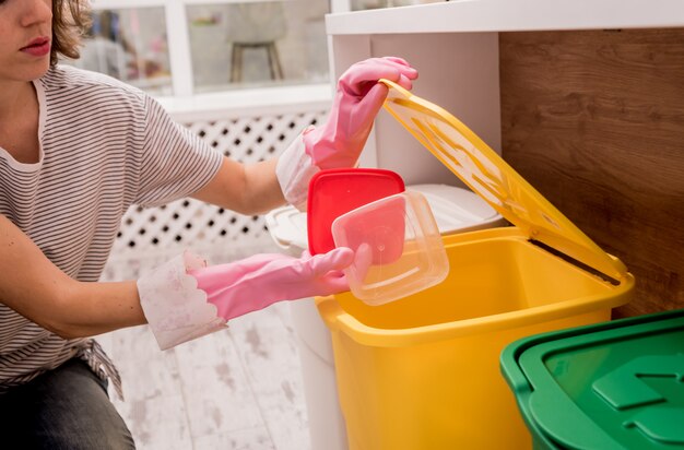 Ragazza che ordina immondizia alla cucina. Concetto di riciclaggio. Zero sprechi