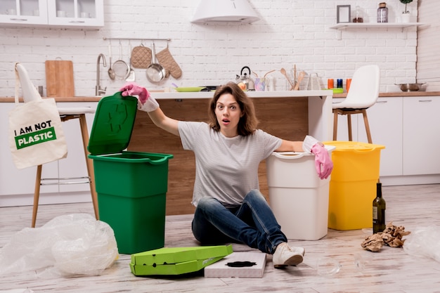 Ragazza che ordina immondizia alla cucina. Concetto di riciclaggio. Zero sprechi