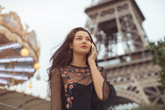 Ragazza che parla al telefono vicino alla Torre Eiffel