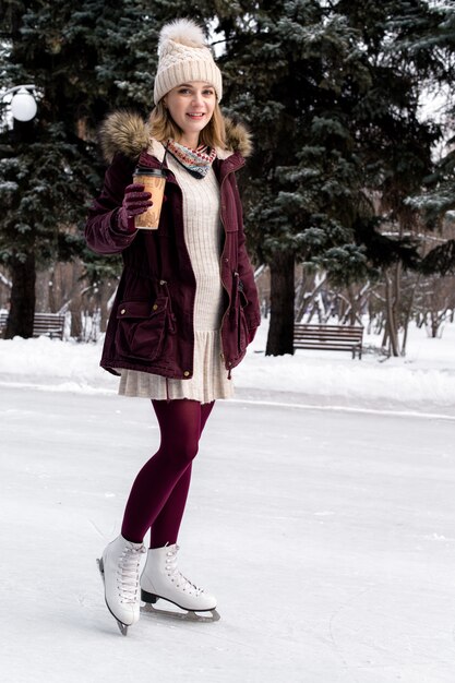 Ragazza che pattina sul lago congelato nel parco nevoso di inverno