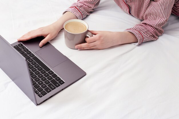 Ragazza che per mezzo del computer portatile e lavora a casa.