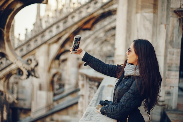 ragazza che per mezzo del suo telefono mentre esplorano il duomo a Milano Italia