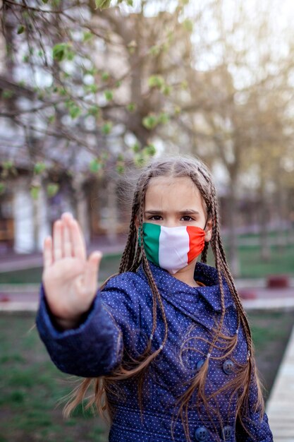 Ragazza che porta via la maschera medica del respiratore nei colori nazionali dell'Italia