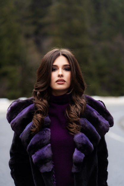 Ragazza che posa alla macchina fotografica sul legno di inverno