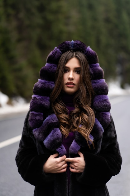 Ragazza che posa alla macchina fotografica sul legno di inverno