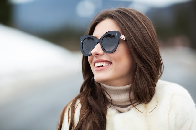 Ragazza che posa sulla strada sul bosco invernale.