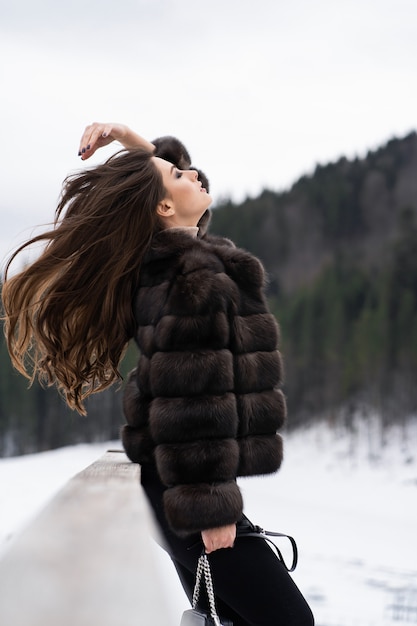 Ragazza che posa sulle montagne di inverno