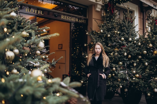 Ragazza che posa vicino agli alberi di Natale