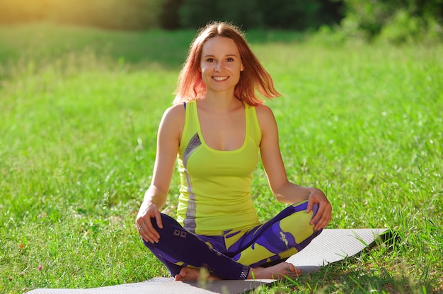 Ragazza che posa yoga fuori nella foresta di mattina