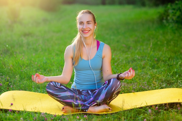 Ragazza che posa yoga fuori nella foresta di mattina