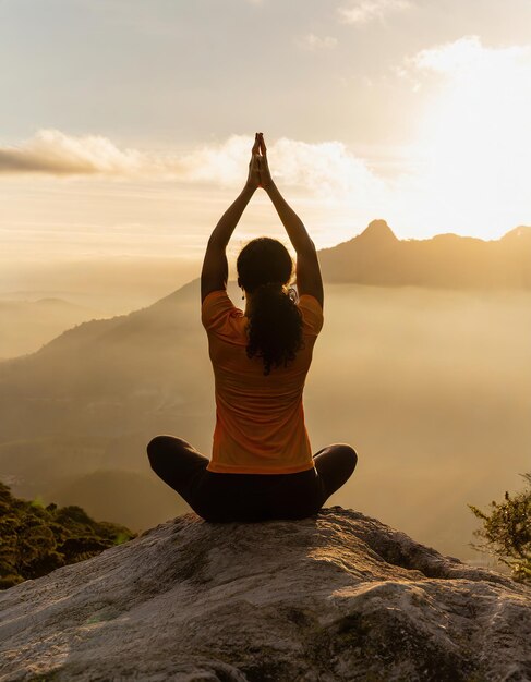 ragazza che pratica yoga su una roccia in montagna