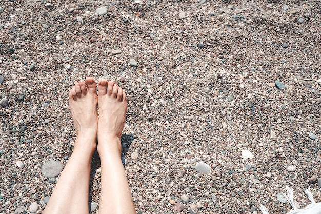 Ragazza che prende il sole e si rilassa sulla spiaggia del mare piedi e gambe femminili sulla spiaggia sotto il sole ricrea...