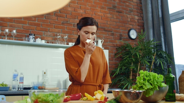 Ragazza che prepara insalata di verdure in cucina Donna che sente l'odore del bulbo di cipolla fresca