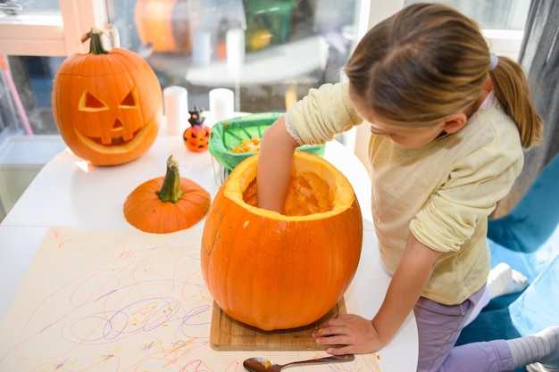 Ragazza che pulisce la zucca di Halloween