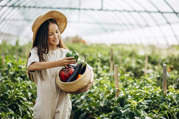 Ragazza che raccoglie verdure in serra