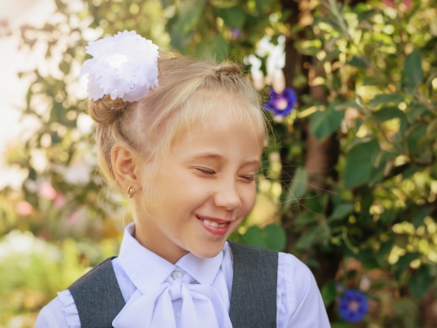 Ragazza che ride in uniforme scolastica con fiocco in testa in autunno Parco.