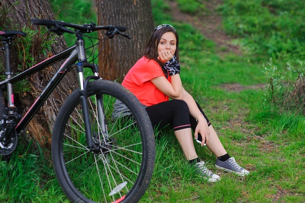 Ragazza che riposa dopo il ciclismo vicino ad un albero