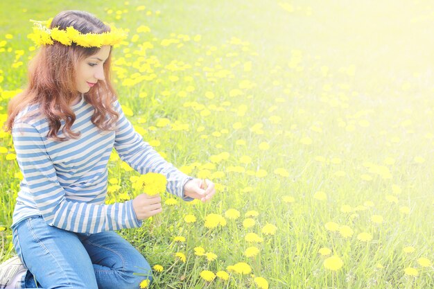 Ragazza che riposa in una giornata di sole in un prato di denti di leone gialli