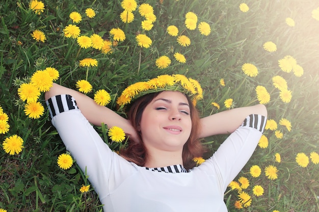 Ragazza che riposa in una giornata di sole in un prato di denti di leone gialli