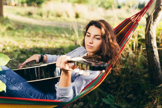 ragazza che riposa su un'amaca con una chitarra nel parco