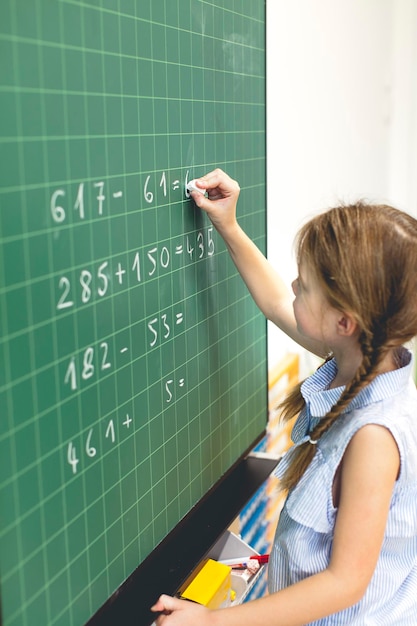 Ragazza che risolve un'equazione matematica sulla lavagna in classe a scuola