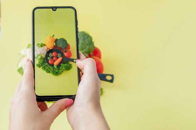 Ragazza che scatta foto di cibo vegetariano con il suo smartphone