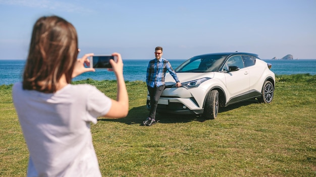 Ragazza che scatta una foto di un ragazzo appoggiato a un'auto