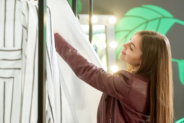 Ragazza che sceglie i vestiti nel negozio per comprare