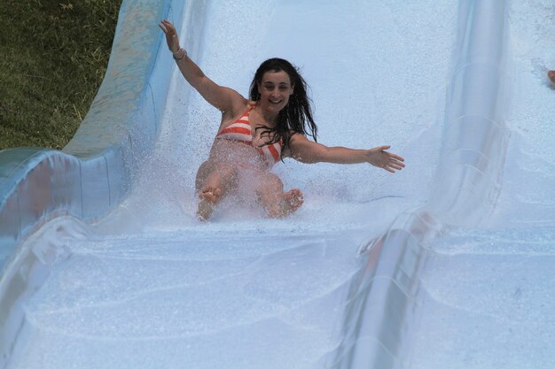 Ragazza che scende e si gode lo scivolo d'acqua nel parco acquatico