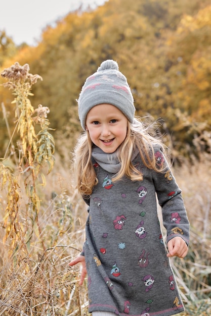 Ragazza che si diverte nel campo di canne secche passeggiata in famiglia autunnale nella foresta