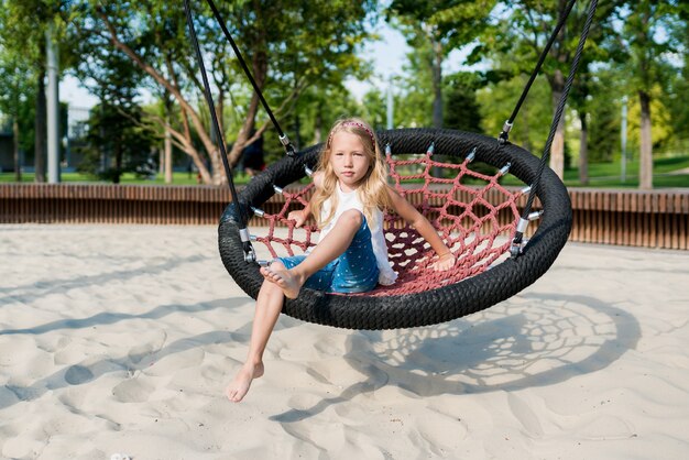 Ragazza che si diverte su una grande altalena nel parco giochi all'esterno