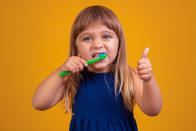 Ragazza che si lava i denti e pollice in alto