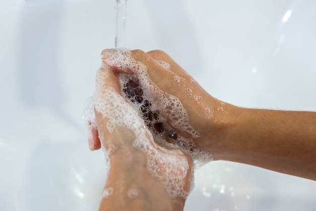 Ragazza che si lava le mani con il sapone in bagno per l'igiene personale e la prevenzione della diffusione di Covid19.