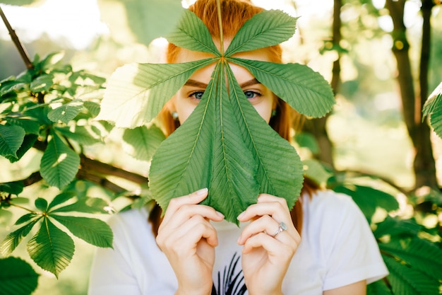 Ragazza che si nasconde dietro la foglia dell'albero