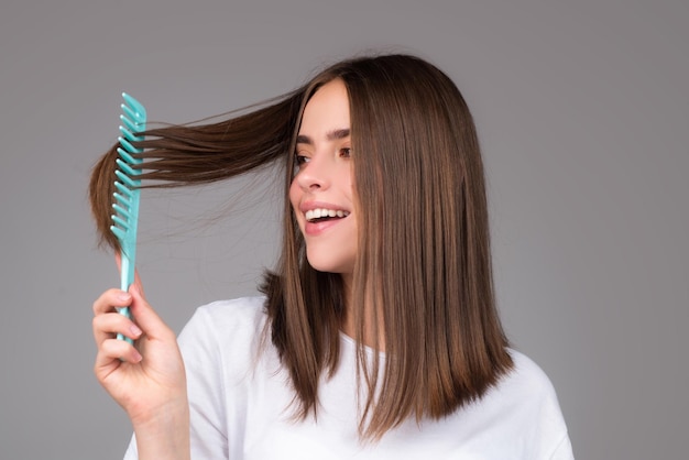 Ragazza che si pettina i capelli bella giovane donna che tiene il pettine i capelli raddrizzati