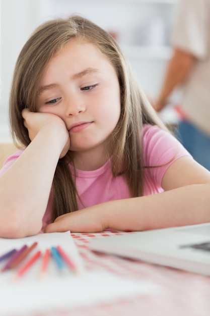 Ragazza che si siede annoiato con le matite di carta e di coloritura