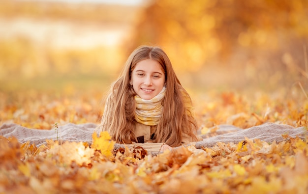 Ragazza che si siede in foglie gialle