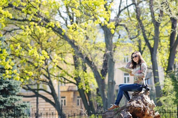 Ragazza che si siede nel parco e leggendo una mappa