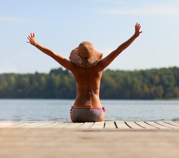 Ragazza che si siede sul molo e guardando il fiume