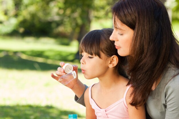 Ragazza che soffia bolle con sua madre nel parco